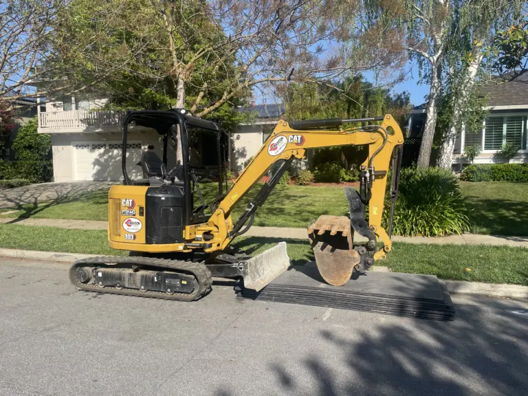 CAT Mini Excavator parked in front of a home