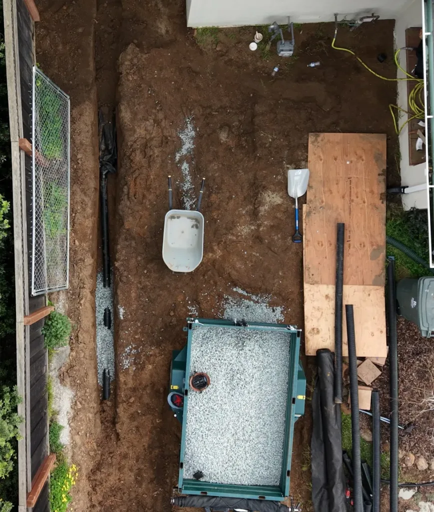 Open trench for french drain installation with gravel ready for placement